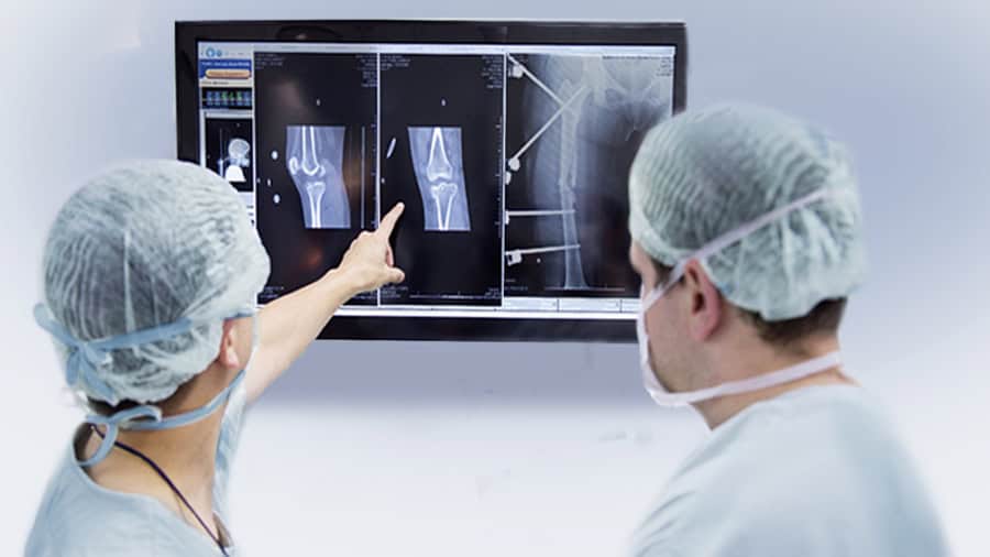 Two surgeons are discussing the healing progress of a fracture in front of an X-ray.